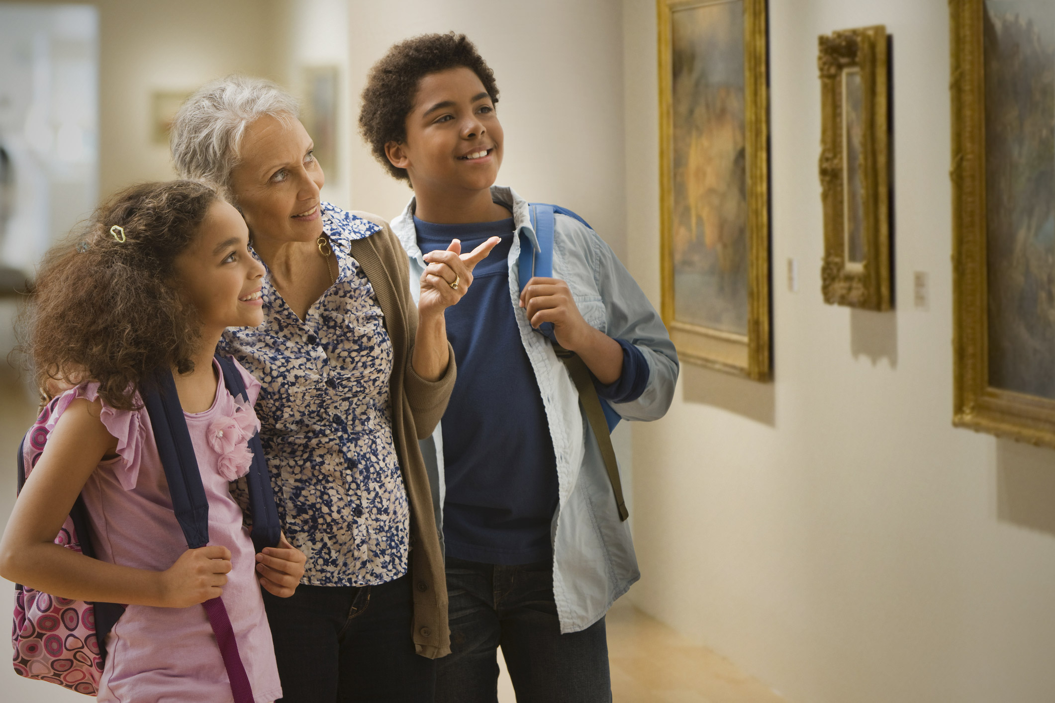 Estudantes e uma pessoa mais velha olhando para um quadro em uma galeria