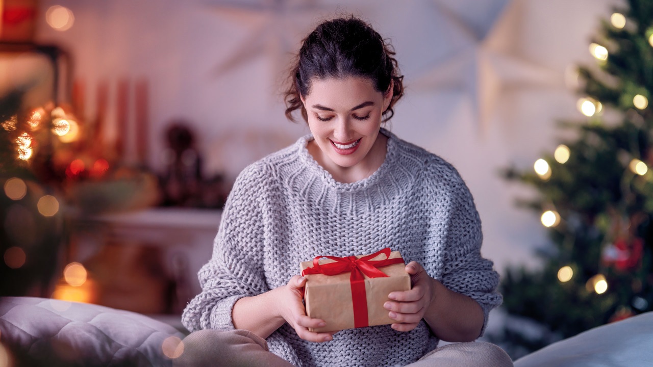 mulher, feliz, segurando um presente de natal